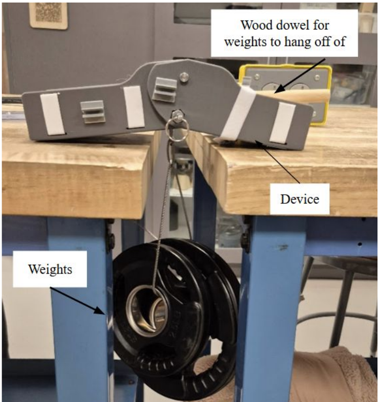 Structural compliance test setup with the brace spanning two tables at 20 degrees extension and a suspended weight plate hanging from a dowel.